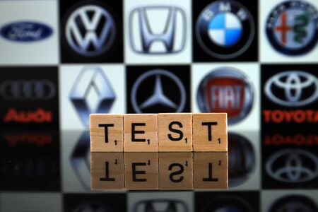 WROCLAW, POLAND - FEBRUARY 19, 2020: Word TEST made of wooden letters, and FORD, VOLKSWAGEN, HONDA, BMW, ALFA ROMEO, AUDI, RENAULT, MERCEDES, FIAT, TOYOTA logos in the background.のeditorial素材
