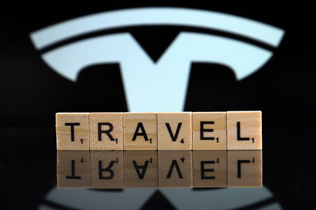WROCLAW, POLAND - FEBRUARY 19, 2020: Word TRAVEL made of wooden letters, and TESLA logo in the background.のeditorial素材