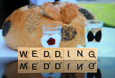 WROCLAW, POLAND - FEBRUARY 28, 2020: The word WEDDING made of scrabble letters, and bread and glasses for the bride and groom in the background. Studio shot.のeditorial素材