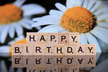 WROCLAW, POLAND - FEBRUARY 28, 2020: The words HAPPY BIRTHDAY made of scrabble letters, and flowers in the background. Studio shot.のeditorial素材