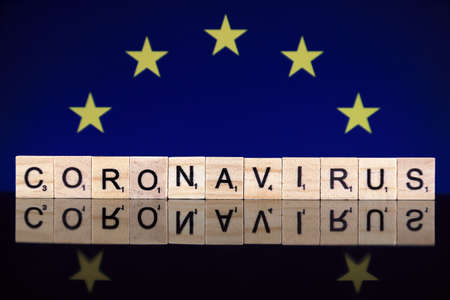 WROCLAW, POLAND - MARCH 28, 2020: Word CORONAVIRUS made of wooden letters, and European Union Flag in the background. Coronavirus (COVID-19) global disease 2020.のeditorial素材