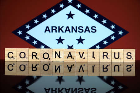 WROCLAW, POLAND - MARCH 28, 2020: Word CORONAVIRUS made of wooden letters, and Arkansas State Flag in the background. Coronavirus (COVID-19) global disease 2020.のeditorial素材