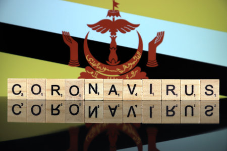 WROCLAW, POLAND - MARCH 28, 2020: Word CORONAVIRUS made of wooden letters, and Brunei Flag in the background. Coronavirus (COVID-19) global disease 2020.のeditorial素材