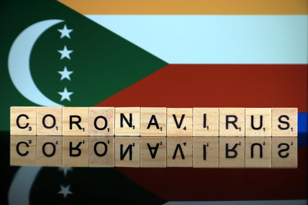 WROCLAW, POLAND - MARCH 28, 2020: Word CORONAVIRUS made of wooden letters, and Comoros Flag in the background. Coronavirus (COVID-19) global disease 2020.のeditorial素材
