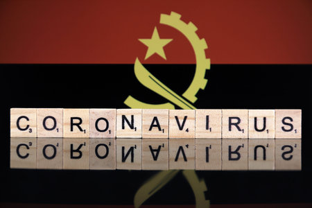 WROCLAW, POLAND - MARCH 28, 2020: Word CORONAVIRUS made of wooden letters, and Angola Flag in the...