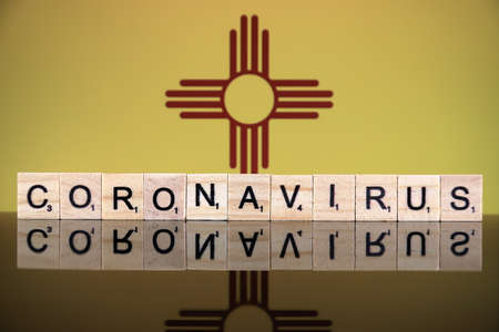 WROCLAW, POLAND - MARCH 28, 2020: Word CORONAVIRUS made of wooden letters, and New Mexico State Flag in the background. Coronavirus (COVID-19) global disease 2020.のeditorial素材