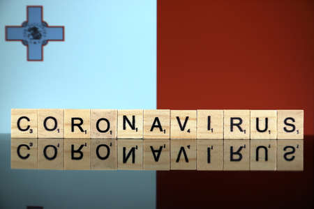 WROCLAW, POLAND - MARCH 28, 2020: Word CORONAVIRUS made of wooden letters, and Malta Flag in the background. Coronavirus (COVID-19) global disease 2020.のeditorial素材
