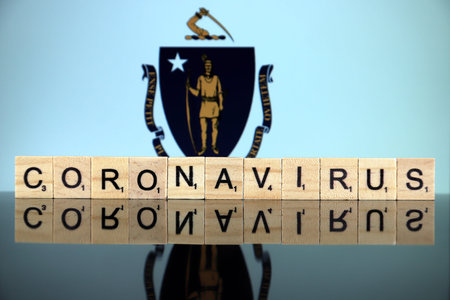 WROCLAW, POLAND - MARCH 28, 2020: Word CORONAVIRUS made of wooden letters, and Massachusetts State...