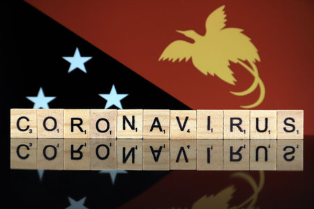 WROCLAW, POLAND - MARCH 28, 2020: Word CORONAVIRUS made of wooden letters, and Papua New Guinea Flag...