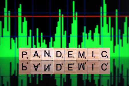 WROCLAW, POLAND - MARCH 30, 2020: The word PANDEMIC made of wooden letters, and green chart in the background. Coronavirus (COVID-19) global disease 2020.のeditorial素材