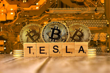 WROCLAW, POLAND - FEBRUARY 10, 2021: Word TESLA made of small wooden letters, and physical version of Bitcoin. Conceptual image for investors in High Technology (Cryptocurrency and electric cars).のeditorial素材