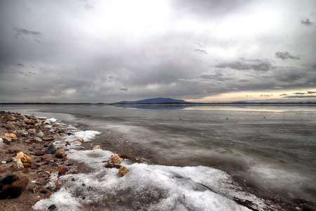 An ice-covered beach by the Mietkowski Lagoon, with the Sleza Mountain in the background. Mietkow near Wroclaw, Poland, Europe.の写真素材