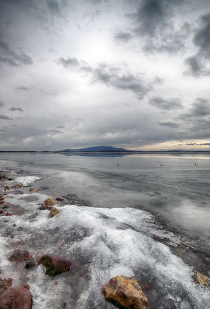 An ice-covered beach by the Mietkowski Lagoon, with the Sleza Mountain in the background. Mietkow near Wroclaw, Poland, Europe.の写真素材