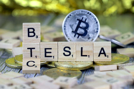 WROCLAW, POLAND - FEBRUARY 10, 2021: Word TESLA and BTC (Bitcoin) made of small wooden letters, and physical version of Bitcoin.のeditorial素材