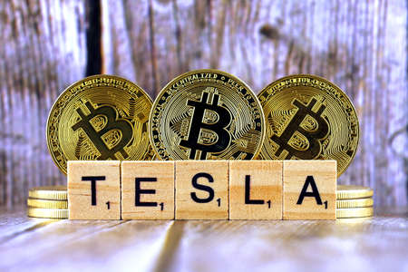 WROCLAW, POLAND - FEBRUARY 10, 2021: Word TESLA made of small wooden letters, and physical version of Bitcoin.のeditorial素材