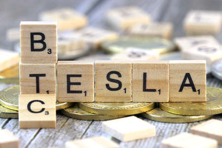WROCLAW, POLAND - FEBRUARY 10, 2021: Word TESLA and BTC (Bitcoin) made of small wooden letters, and physical version of Bitcoin.のeditorial素材