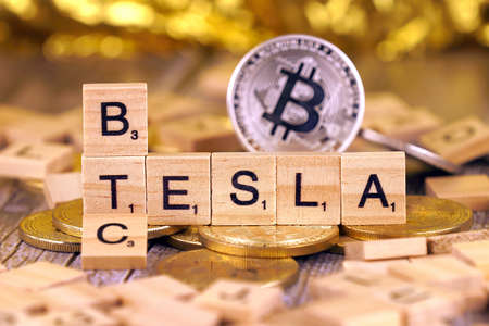 WROCLAW, POLAND - FEBRUARY 10, 2021: Word TESLA and BTC (Bitcoin) made of small wooden letters, and physical version of Bitcoin.のeditorial素材
