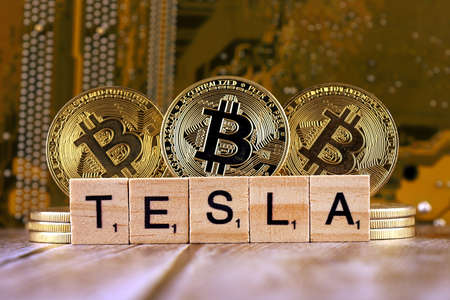WROCLAW, POLAND - FEBRUARY 10, 2021: Word TESLA made of small wooden letters, and physical version of Bitcoin.のeditorial素材
