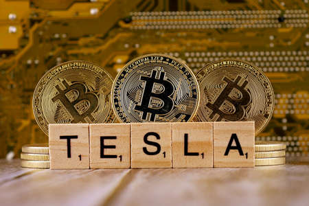 WROCLAW, POLAND - FEBRUARY 10, 2021: Word TESLA made of small wooden letters, and physical version of Bitcoin.のeditorial素材