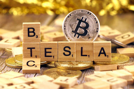 WROCLAW, POLAND - FEBRUARY 10, 2021: Word TESLA and BTC (Bitcoin) made of small wooden letters, and physical version of Bitcoin.のeditorial素材