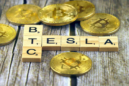 WROCLAW, POLAND - FEBRUARY 10, 2021: Word TESLA and BTC (Bitcoin) made of small wooden letters, and physical version of Bitcoin.のeditorial素材