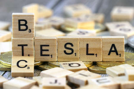 WROCLAW, POLAND - FEBRUARY 10, 2021: Word TESLA and BTC (Bitcoin) made of small wooden letters, and physical version of Bitcoin.のeditorial素材