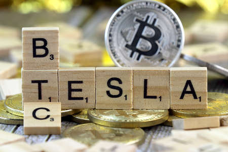 WROCLAW, POLAND - FEBRUARY 10, 2021: Word TESLA and BTC (Bitcoin) made of small wooden letters, and physical version of Bitcoin.のeditorial素材