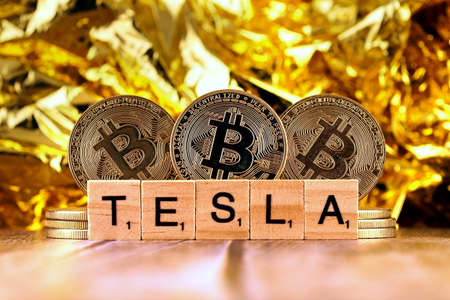 WROCLAW, POLAND - FEBRUARY 10, 2021: Word TESLA made of small wooden letters, and physical version of Bitcoin.のeditorial素材