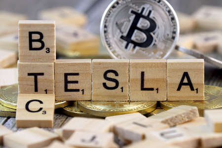 WROCLAW, POLAND - FEBRUARY 10, 2021: Word TESLA and BTC (Bitcoin) made of small wooden letters, and physical version of Bitcoin.のeditorial素材