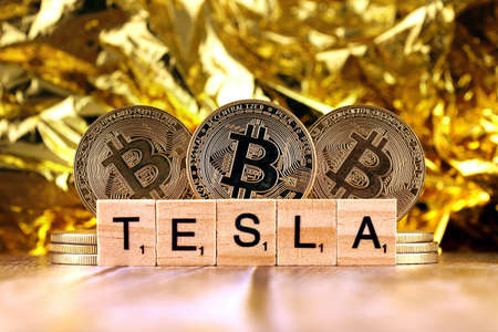 WROCLAW, POLAND - FEBRUARY 10, 2021: Word TESLA made of small wooden letters, and physical version of Bitcoin.のeditorial素材