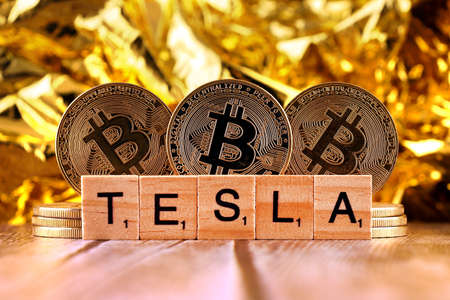 WROCLAW, POLAND - FEBRUARY 10, 2021: Word TESLA made of small wooden letters, and physical version of Bitcoin.のeditorial素材