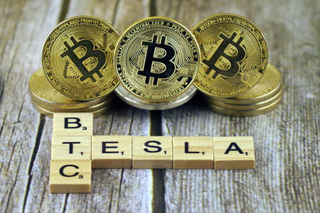WROCLAW, POLAND - FEBRUARY 10, 2021: Word TESLA and BTC (Bitcoin) made of small wooden letters, and physical version of Bitcoin.のeditorial素材