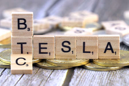 WROCLAW, POLAND - FEBRUARY 10, 2021: Word TESLA and BTC (Bitcoin) made of small wooden letters, and physical version of Bitcoin.のeditorial素材