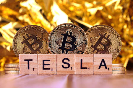 WROCLAW, POLAND - FEBRUARY 10, 2021: Word TESLA made of small wooden letters, and physical version of Bitcoin.のeditorial素材