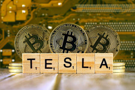 WROCLAW, POLAND - FEBRUARY 10, 2021: Word TESLA made of small wooden letters, and physical version of Bitcoin.のeditorial素材