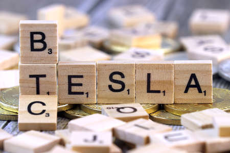 WROCLAW, POLAND - FEBRUARY 10, 2021: Word TESLA and BTC (Bitcoin) made of small wooden letters, and physical version of Bitcoin.のeditorial素材