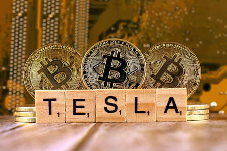 WROCLAW, POLAND - FEBRUARY 10, 2021: Word TESLA made of small wooden letters, and physical version of Bitcoin.のeditorial素材