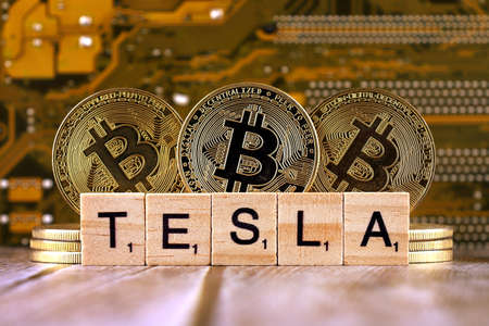 WROCLAW, POLAND - FEBRUARY 10, 2021: Word TESLA made of small wooden letters, and physical version of Bitcoin.のeditorial素材