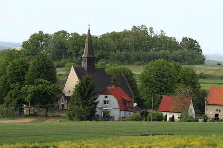 WROCLAW, POLAND - MAY 24, 2021: St. Martin Church in Gogolow at the foot of Sleza Mountain, surrounded by fields of flowering rape.のeditorial素材