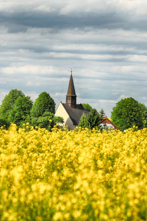 WROCLAW, POLAND - MAY 24, 2021: St. Martin Church in Gogolow at the foot of Sleza Mountain, surrounded by fields of flowering rape.のeditorial素材