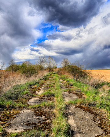Empty, local road among fields on a stormy day on the last days of April. Spring landscape with beautiful clouds.の写真素材