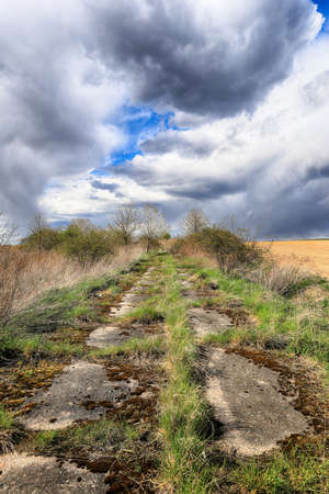 Empty, local road among fields on a stormy day on the last days of April. Spring landscape with beautiful clouds.の写真素材