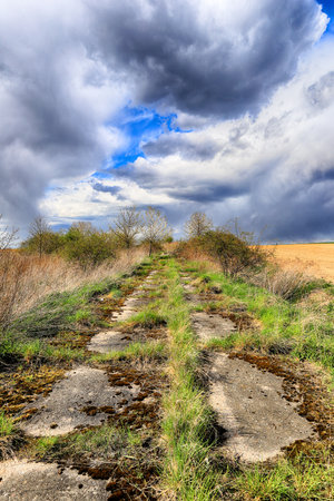 Empty, local road among fields on a stormy day on the last days of April. Spring landscape with beautiful clouds.の写真素材