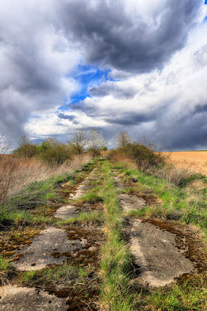 Empty, local road among fields on a stormy day on the last days of April. Spring landscape with beautiful clouds.の写真素材