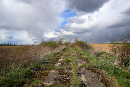 Empty, local road among fields on a stormy day on the last days of April. Spring landscape with beautiful clouds.の写真素材