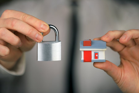 A businessman in a white shirt and black tie holds a silver padlock and miniature house in his hands. home security.の写真素材
