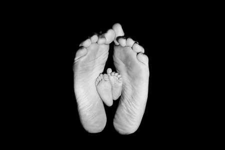 FOOTS OF A BEAUTIFUL BABY. SHOT IN STUDIO. ISOLATED ON BLACK.の写真素材