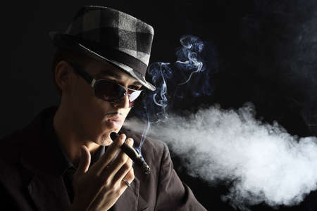 Portrait of a handsome young man in elegant suit smoking a cigar.の写真素材