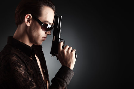 Portrait of a handsome young man holding a gun..