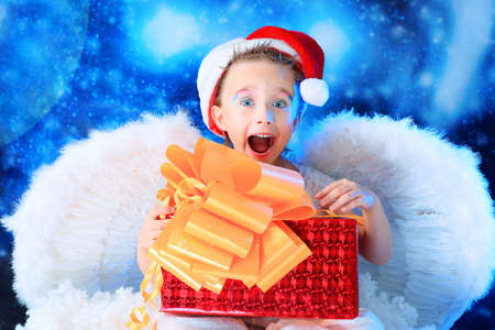Beautiful little angelic child  with a present at a stellar sky.の写真素材